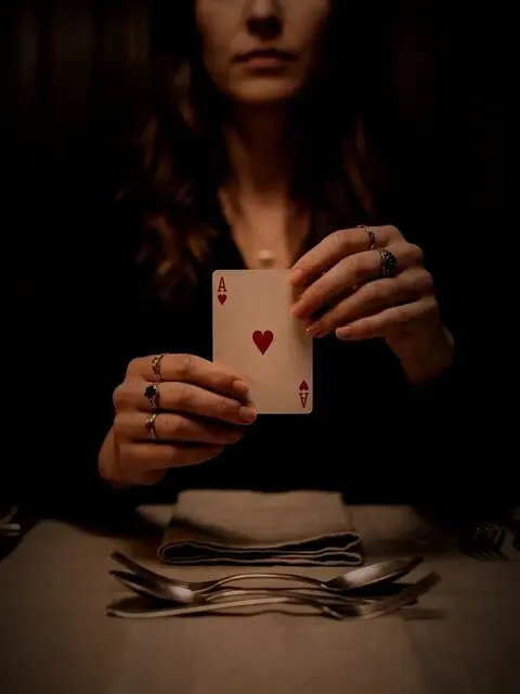 Hände mit Spielkarten im Kerzenlicht.